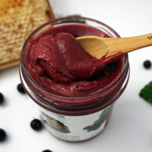 miód z czarnymi porzeczkami z łyżeczką od góry bokiem